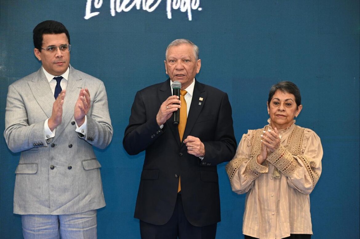 l presidente ejecutivo de Banreservas, doctor Leonardo Aguilera, habla en la feria ANATO 2026. Desde la izquierda, el ministro de Turismo, David Collado; y la presidenta del Voluntariado Banreservas, Carmen Quijano.